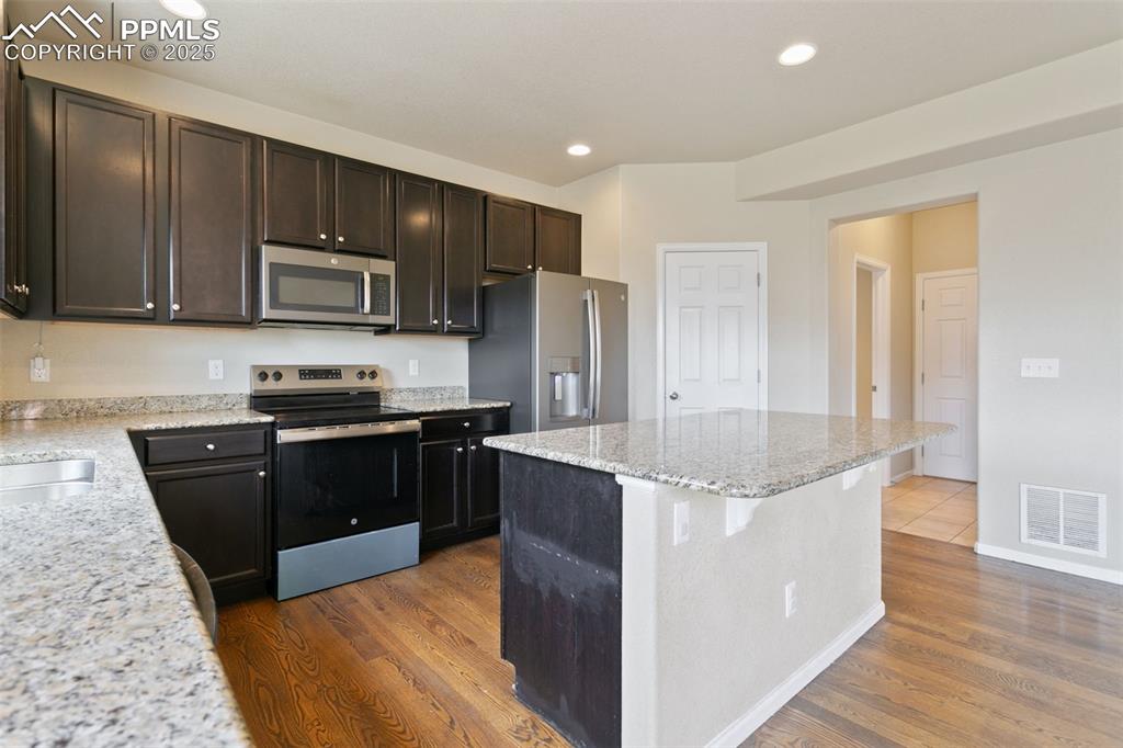 Image 17 of 41: Kitchen with appliances with stainless steel finishes, dark wood-type floor