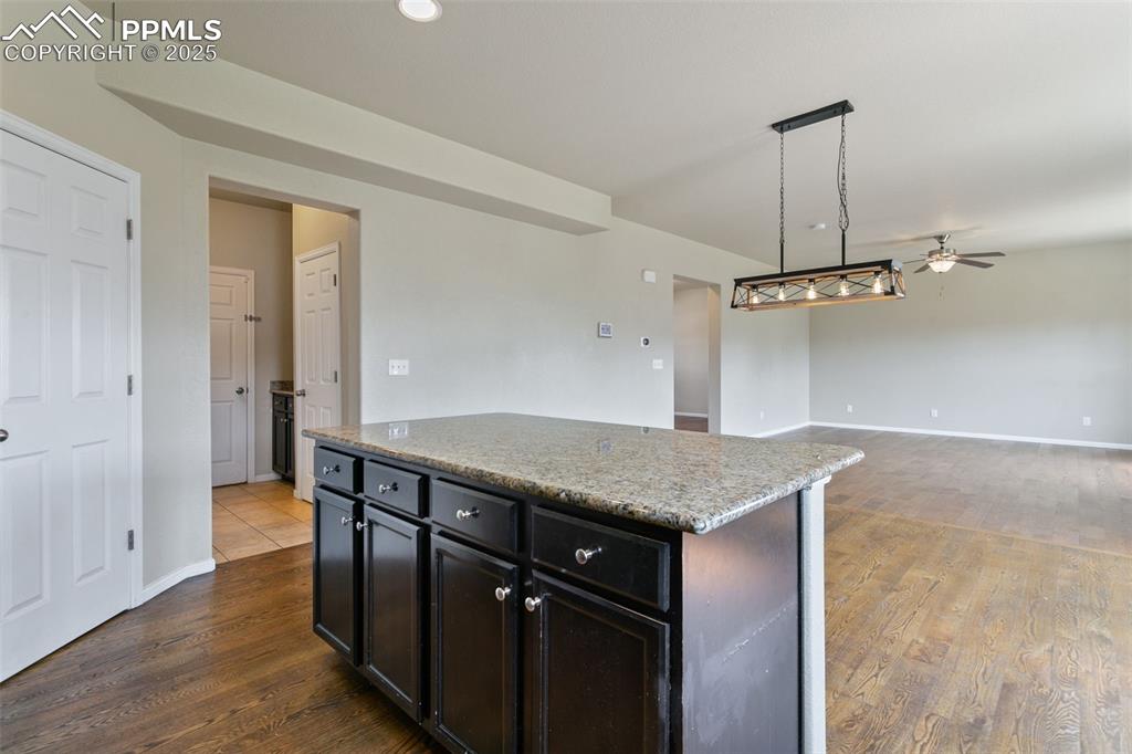 Image 19 of 41: Kitchen with dark wood finished floors, ceiling fan, hanging light fixtures