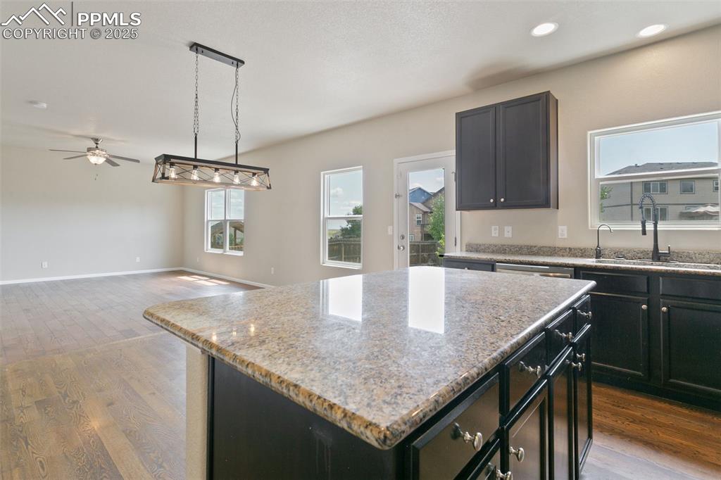 Image 20 of 41: Kitchen with wood finished floors, a kitchen island, light stone counters, 
