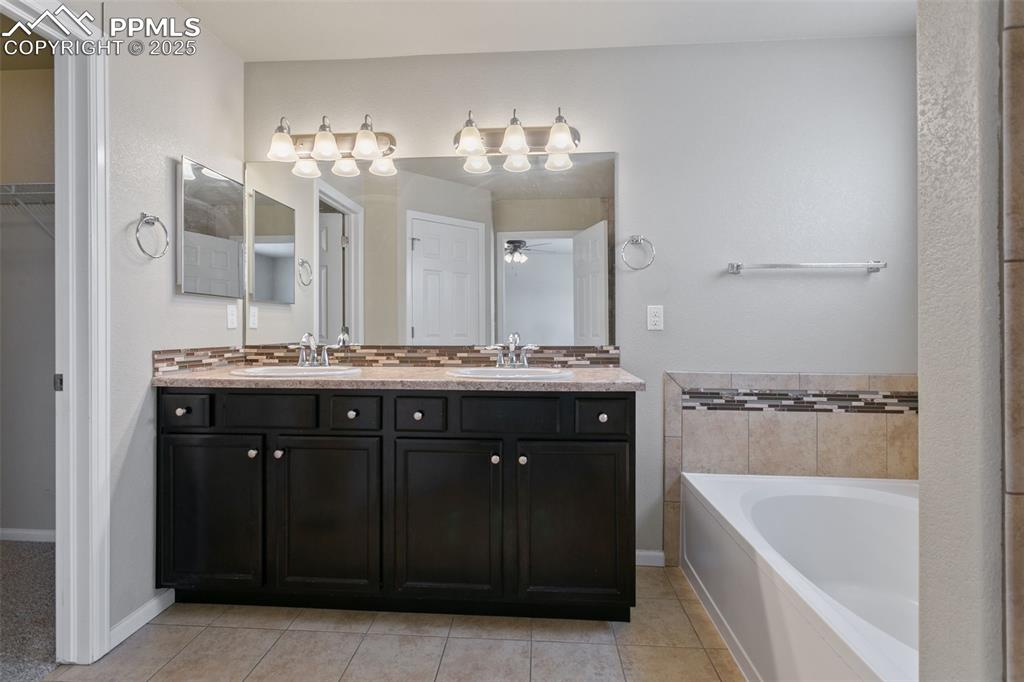 Image 28 of 41: Full bath featuring double vanity, a garden tub, tile patterned flooring, a