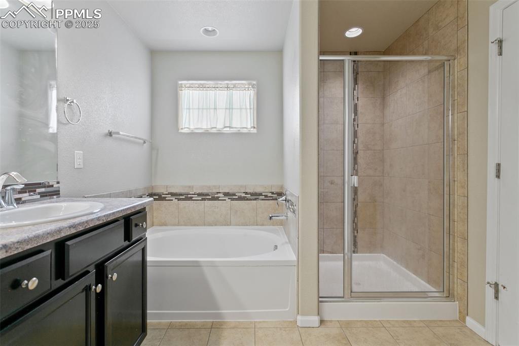 Image 29 of 41: Full bath featuring vanity, a bath, a stall shower, tile patterned floors, 