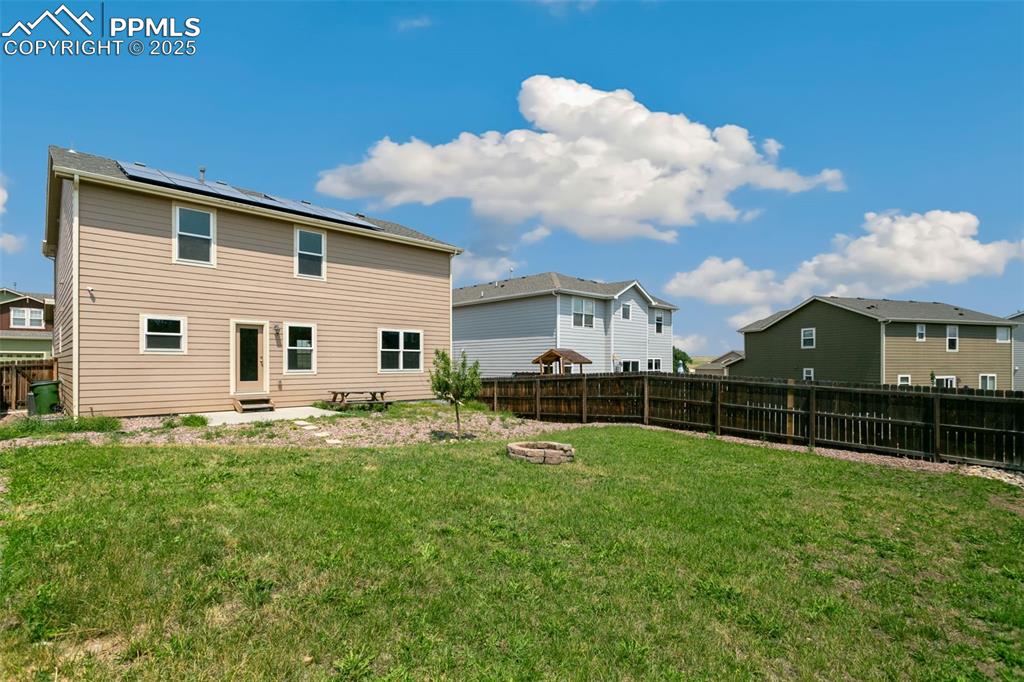 Image 40 of 41: Rear view of house with roof mounted solar panels, a fenced backyard, a res