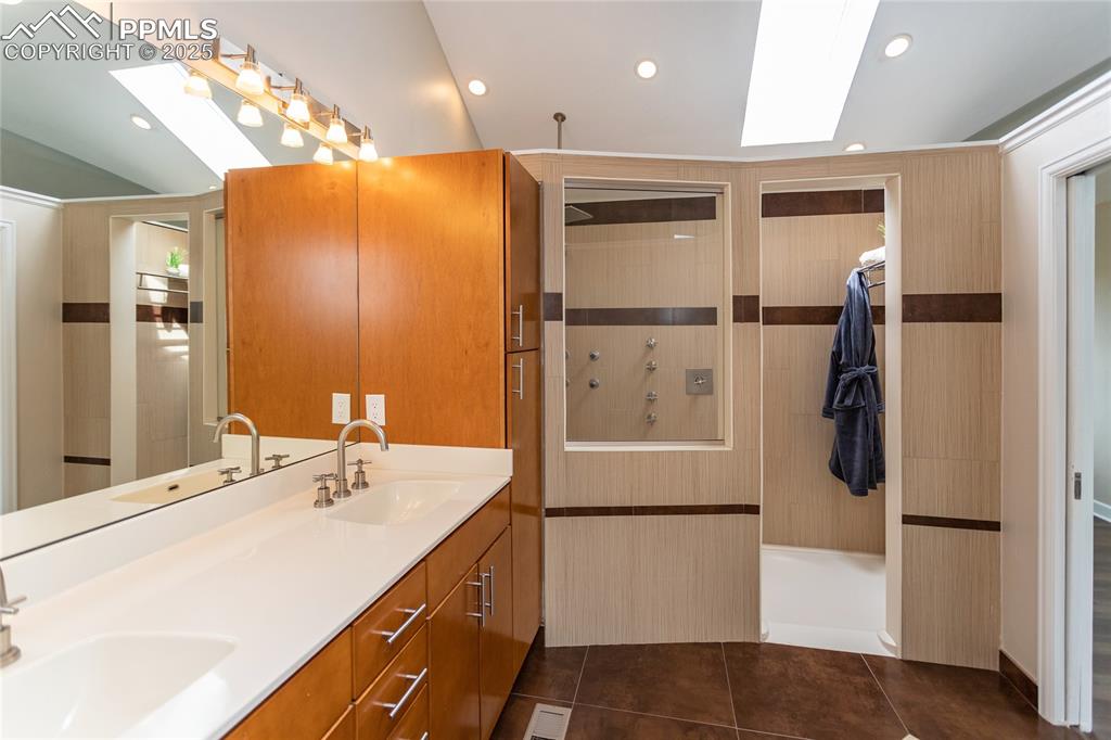 Image 29 of 50: Primary bathroom features solid surface counters, skylight and huge spa sho