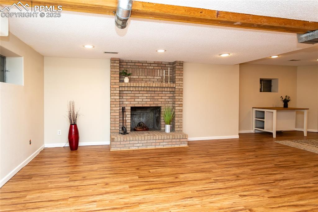 Image 42 of 50: Large family room in the basement with a brick fireplace.