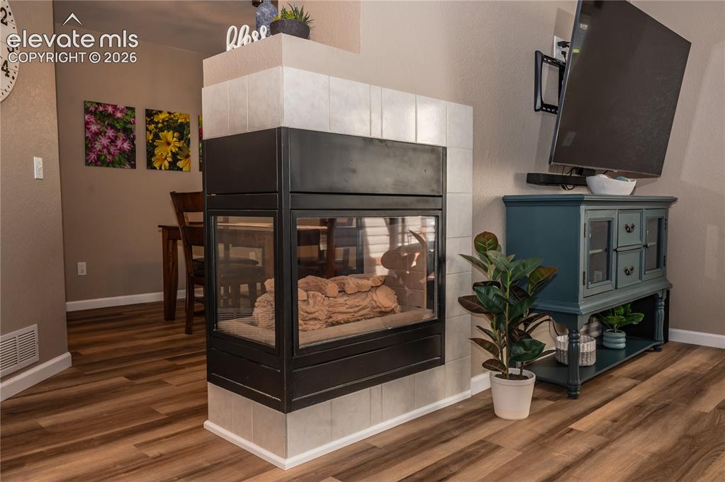Image 8 of 34: 3-sided fireplace separates living and dining rooms