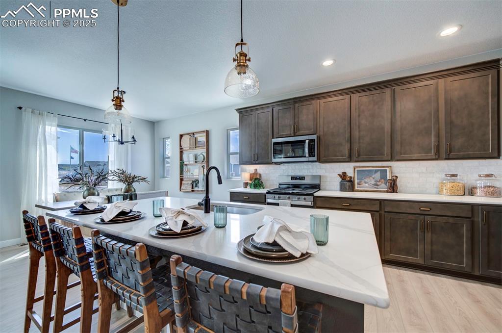 Image 11 of 44: Kitchen with stainless steel appliances, dark brown cabinets, a sink, and a