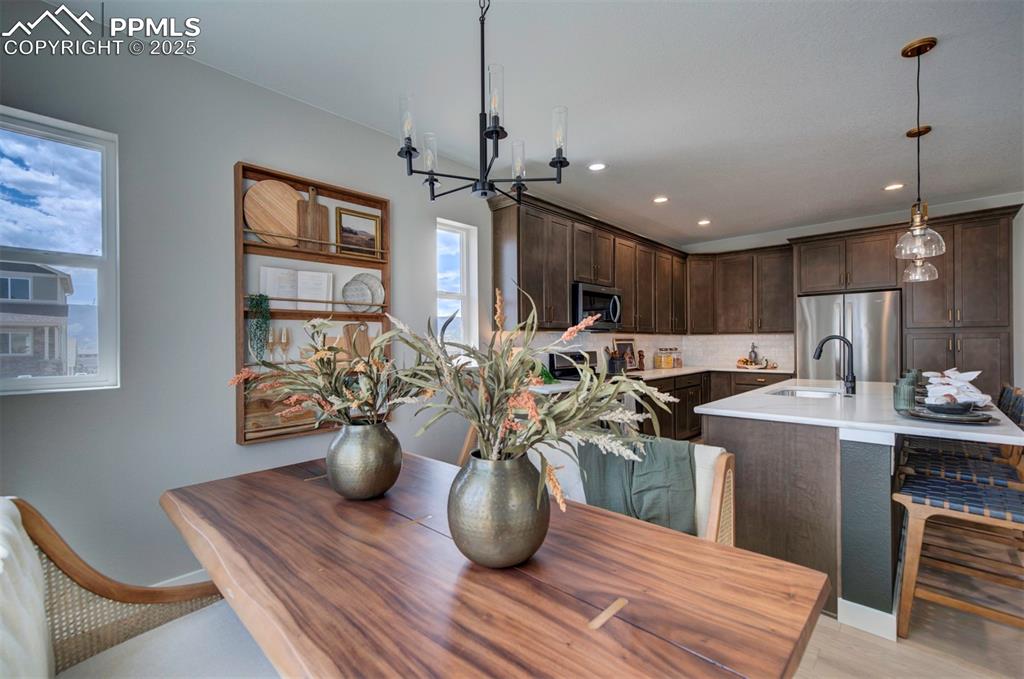 Image 14 of 44: Dining area with light wood-style floors, baseboards, an inviting chandelie