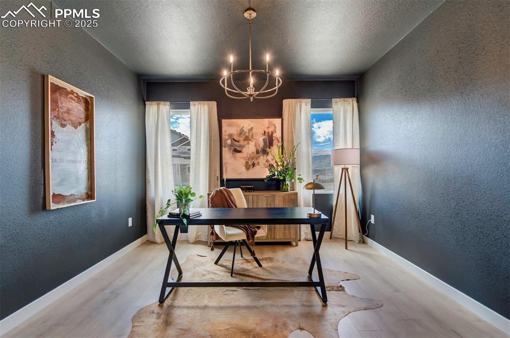 Image 18 of 44: Office featuring an inviting chandelier, a textured wall, a wealth of natur