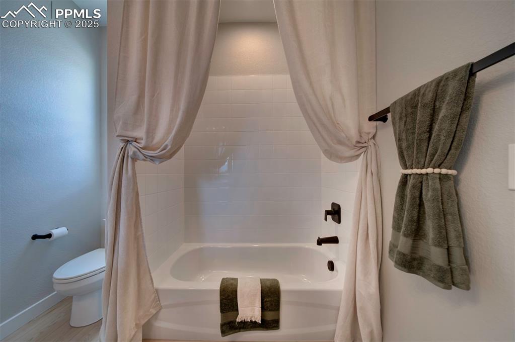 Image 21 of 44: Bathroom with shower / bath combo with shower curtain, baseboards, wood fin