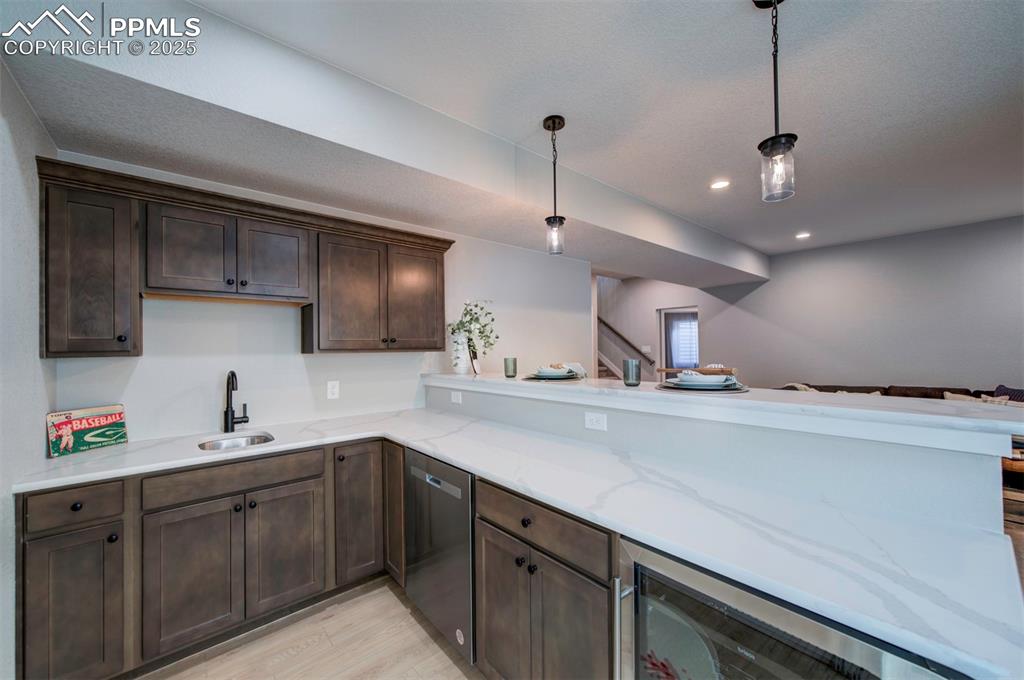 Image 28 of 44: Kitchen with wine cooler, dark brown cabinetry, light wood-type flooring, a