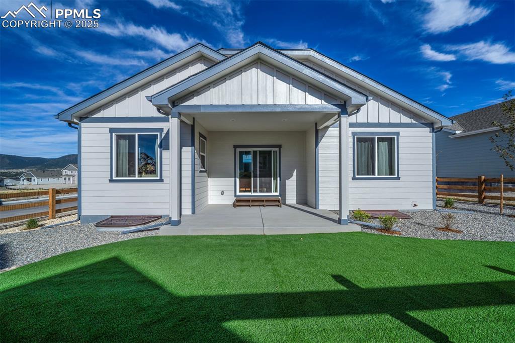 Image 3 of 44: Rear view of property with board and batten siding, a patio, a yard, and fe