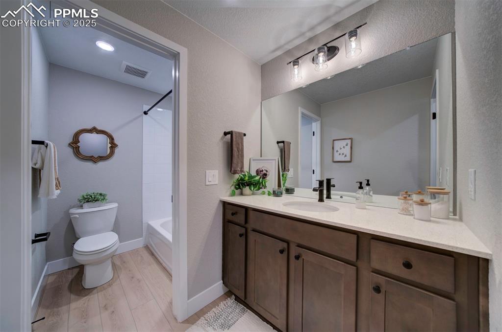 Image 33 of 44: Bathroom featuring bathtub / shower combination, vanity, toilet, wood finis