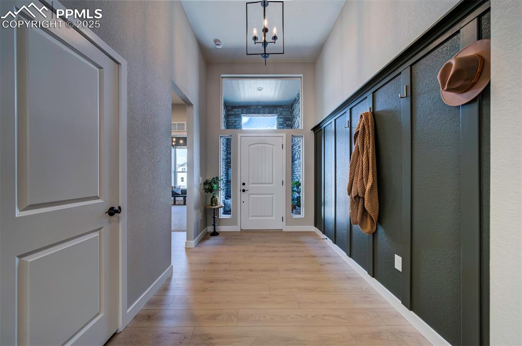 Image 5 of 44: Doorway with a textured wall, a notable chandelier, baseboards, and light w