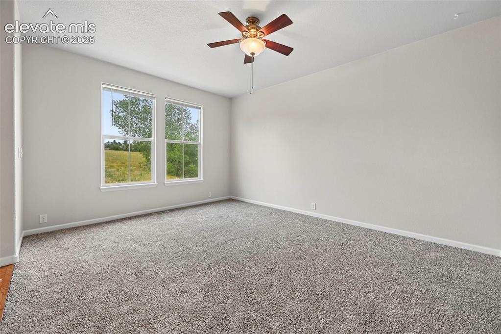 Image 10 of 33: Spacious room featuring neutral paint, gray carpeting, a ceiling fan with i