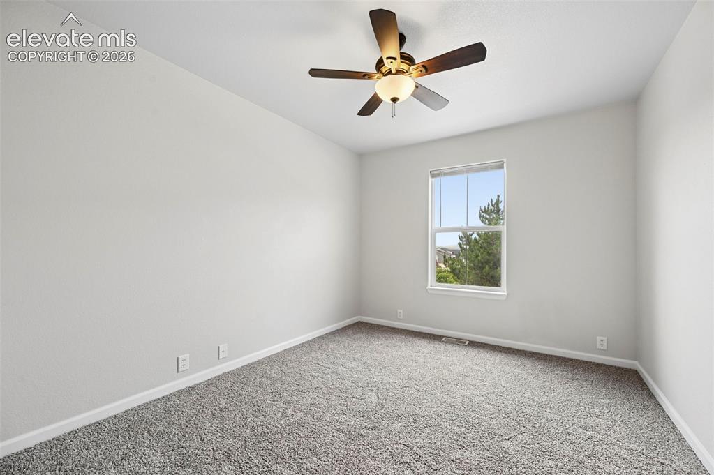 Image 11 of 33: Neutral-toned room featuring a single window, a ceiling fan with integrated
