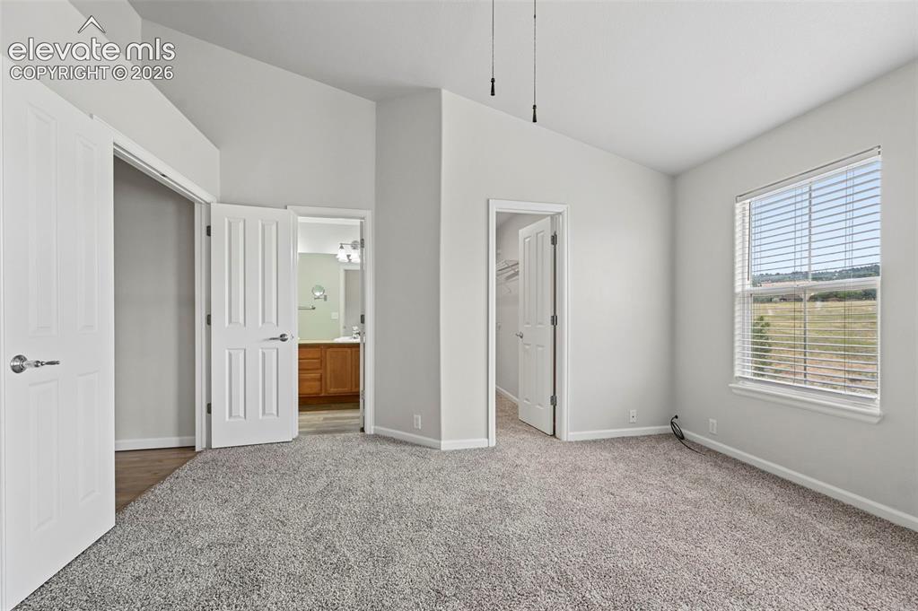 Image 12 of 33: Spacious room featuring vaulted ceilings, light gray carpeting, a large win