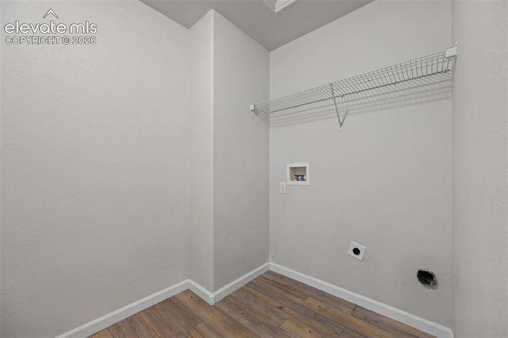 Image 15 of 33: Dedicated laundry area featuring wood-finish flooring, light gray walls, an