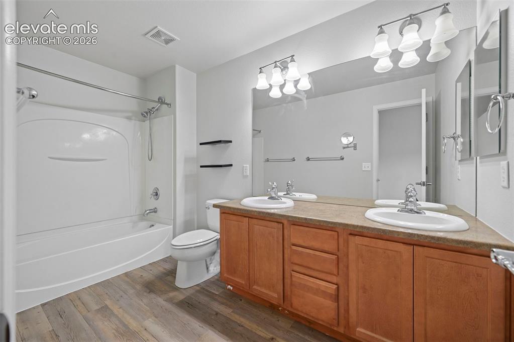 Image 17 of 33: Bathroom featuring a dual vanity with wood-finish cabinetry and integrated