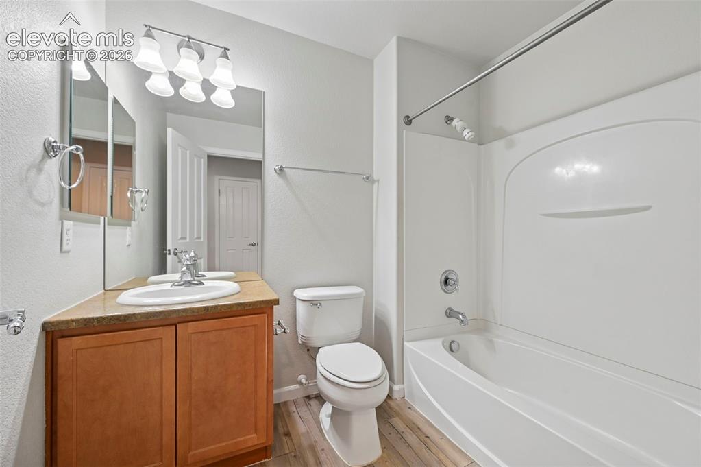Image 18 of 33: Bathroom featuring a wood-finish vanity with an integrated sink, a large mi