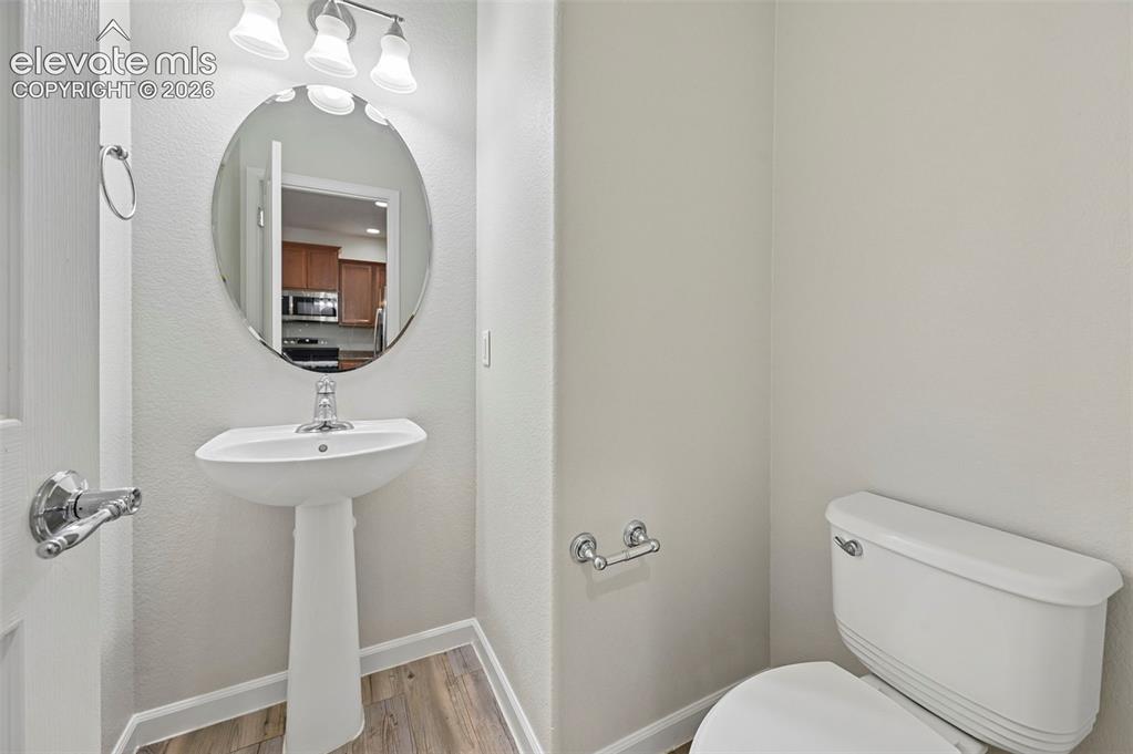 Image 19 of 33: Pedestal sink with chrome faucet, oval mirror, and three-bulb vanity light