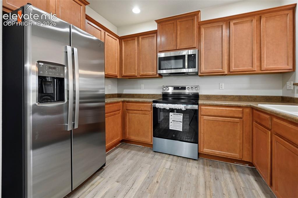 Image 2 of 33: Kitchen featuring wood-finish cabinetry, stainless steel appliances, lamina