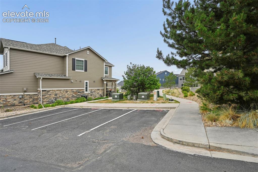 Image 21 of 33: Exterior featuring tan horizontal siding, stone veneer accents, dark shutte