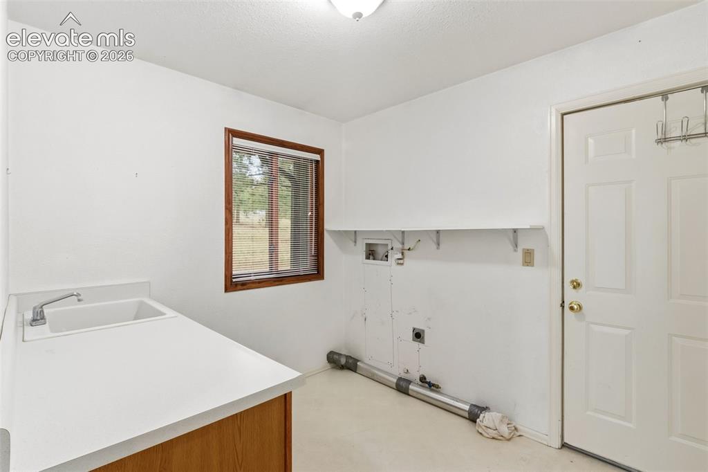 Image 26 of 29: Functional laundry and utility room with garage access, storage space, and