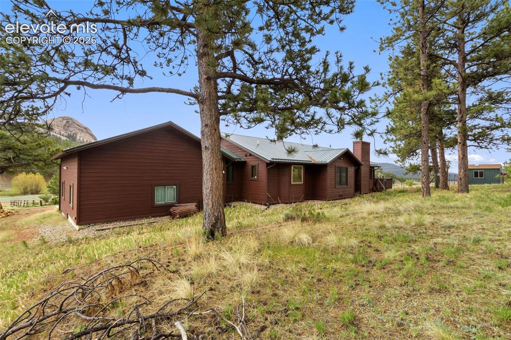 Image 28 of 29: Side exterior view highlighting the wooded setting, natural landscape, and