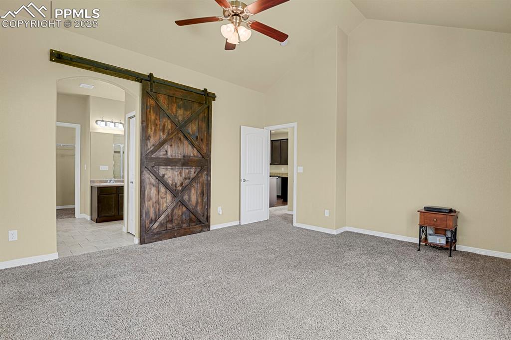 Image 19 of 33: Spacious and private main level master suite with barn door, beautiful view