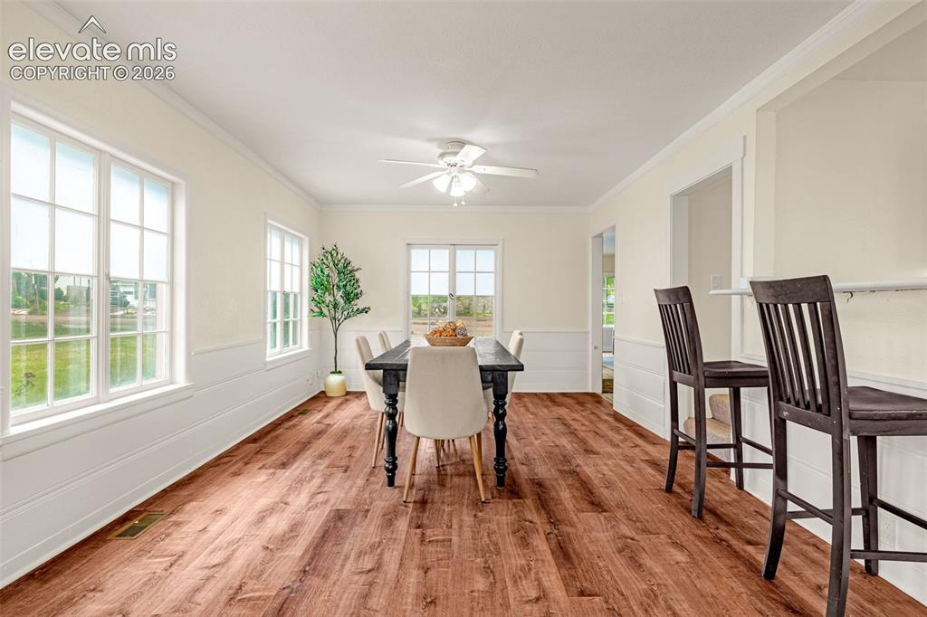 Image 10 of 50: Expansive dining area featuring wood-finish flooring, white wainscoting, mu