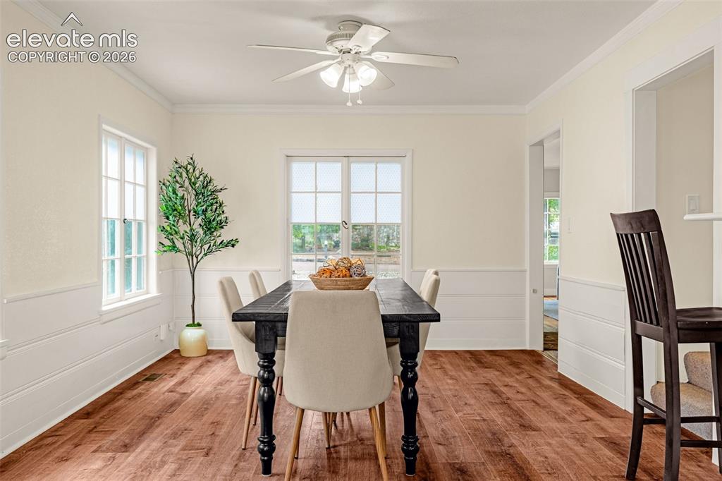 Image 11 of 50: Wood-finish flooring, white paneled wainscoting, crown molding, white trim