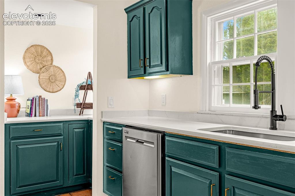 Image 15 of 50: Kitchen featuring teal cabinetry, light countertops, a stainless steel dish
