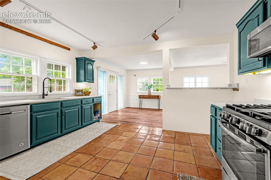 Image 19 of 50: Kitchen featuring tile flooring, teal cabinetry, stainless steel appliances