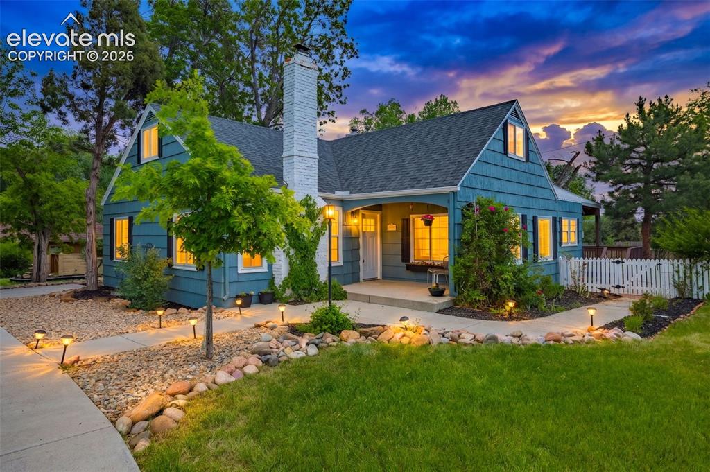 Image 2 of 50: Blue siding exterior with dormer windows, a white brick chimney, and a cove