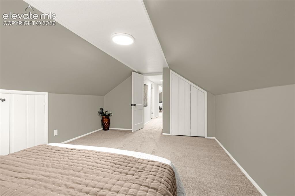Image 20 of 50: Sloped ceilings with recessed lighting, neutral wall paint, and soft carpet