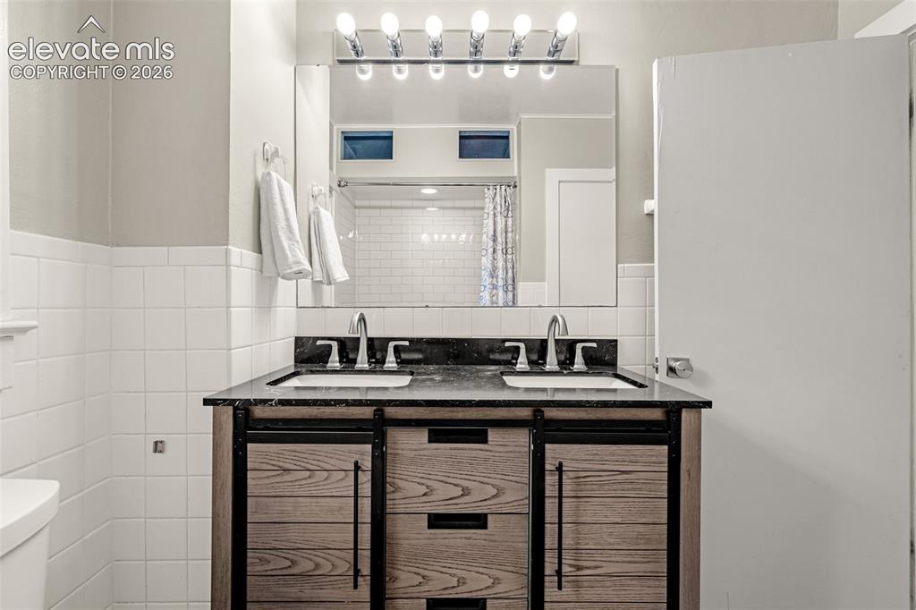 Image 25 of 50: Double vanity with black countertop and undermount sinks, wood-finish cabin