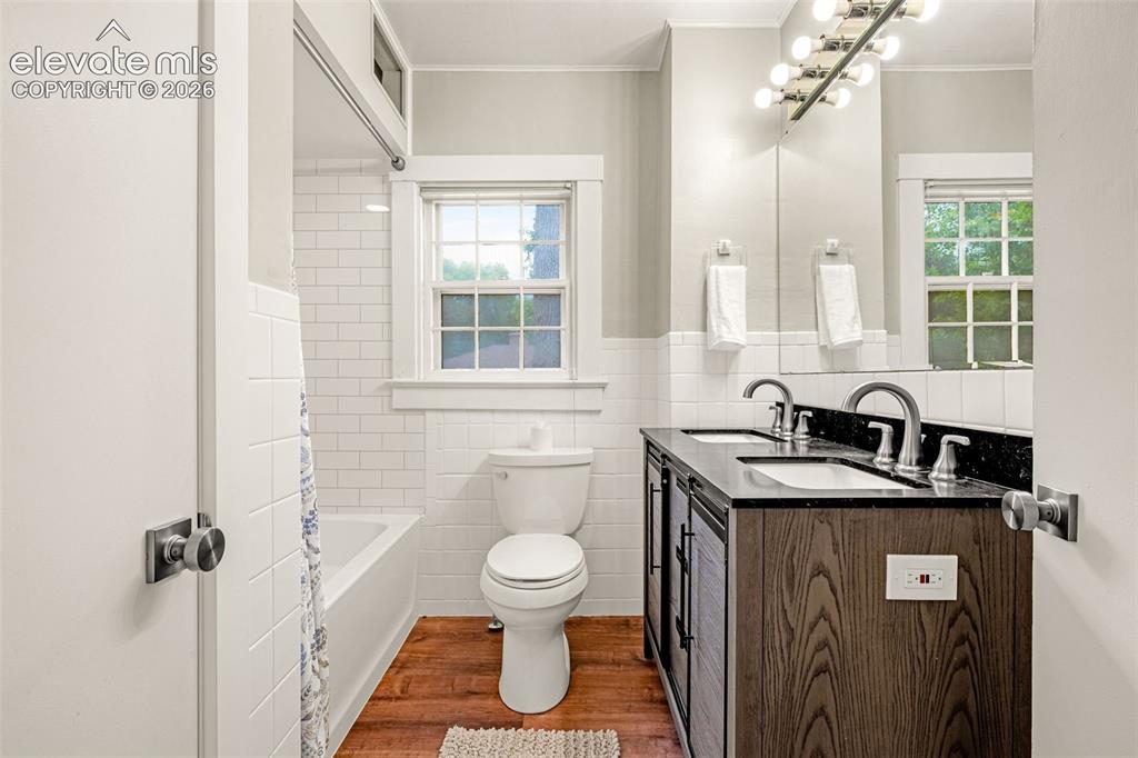 Image 26 of 50: Dual vanity with dark wood-finish cabinetry and dark stone countertop