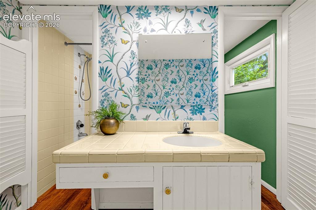 Image 27 of 50: Vanity with an integrated sink and tile countertop, wood-finish flooring, w
