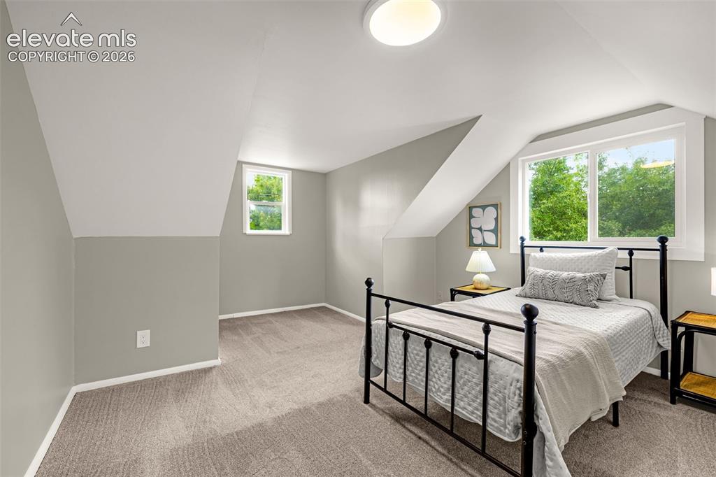Image 29 of 50: Vaulted ceiling with a flush-mount light fixture, two windows, and neutral 