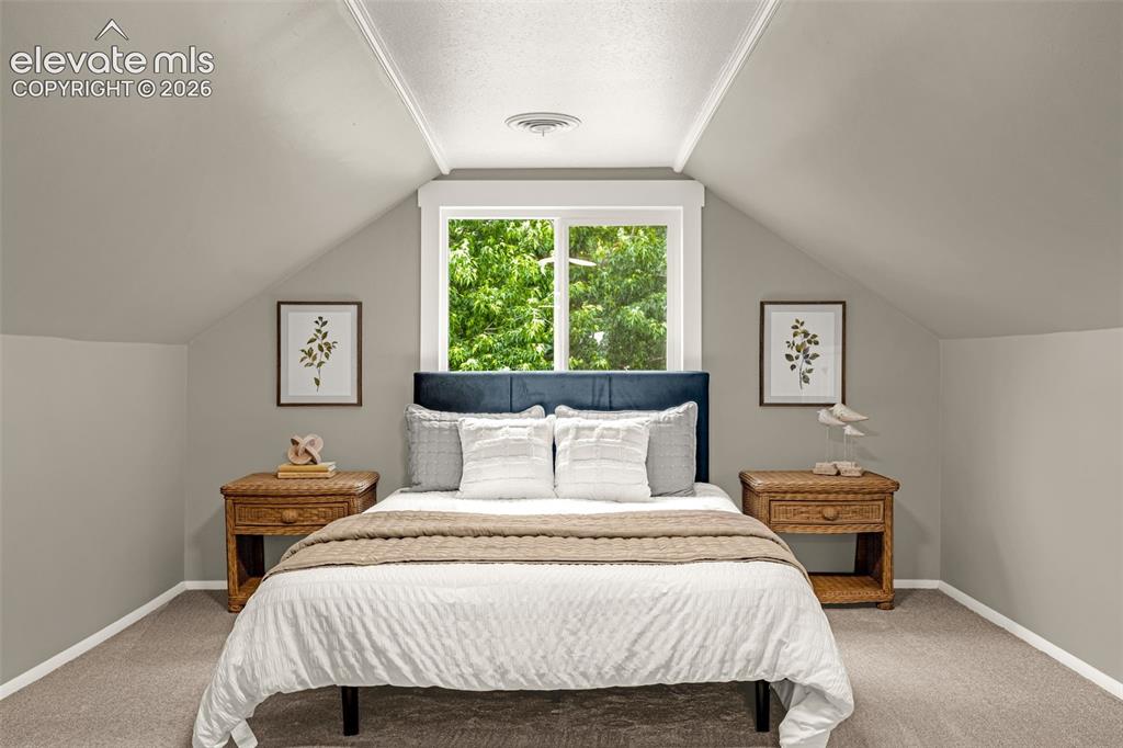 Image 31 of 50: Vaulted ceiling with a central window, carpeted flooring, and sloped walls