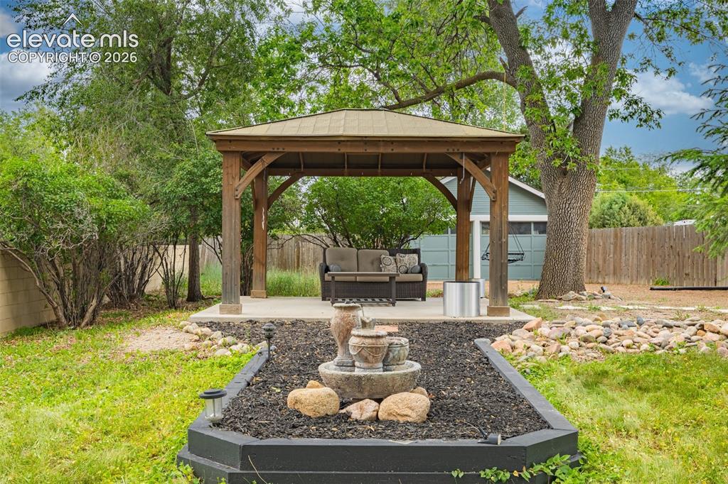 Image 37 of 50: Wood-frame gazebo with a metal roof on a concrete patio