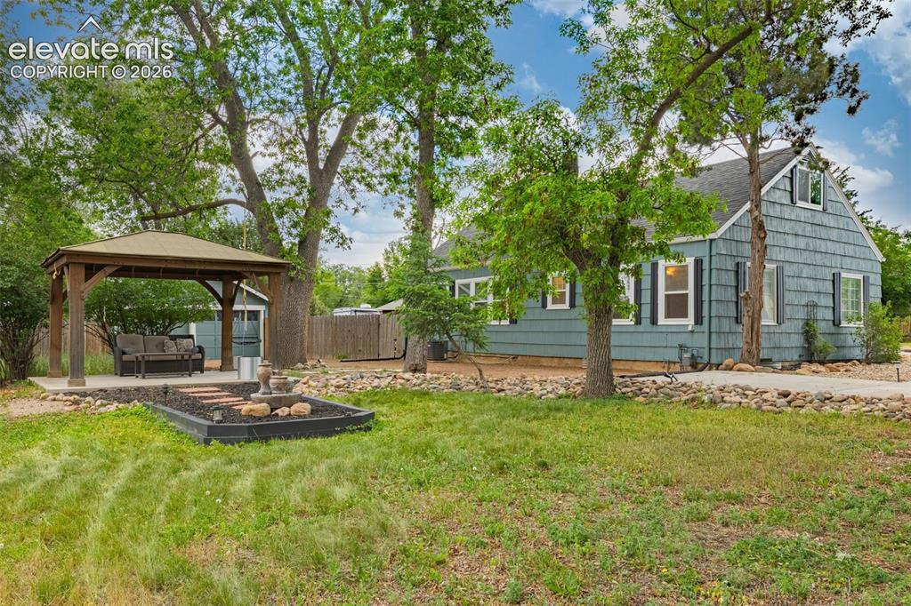 Image 38 of 50: Gazebo with a solid roof and concrete pad, decorative fountain, landscaping