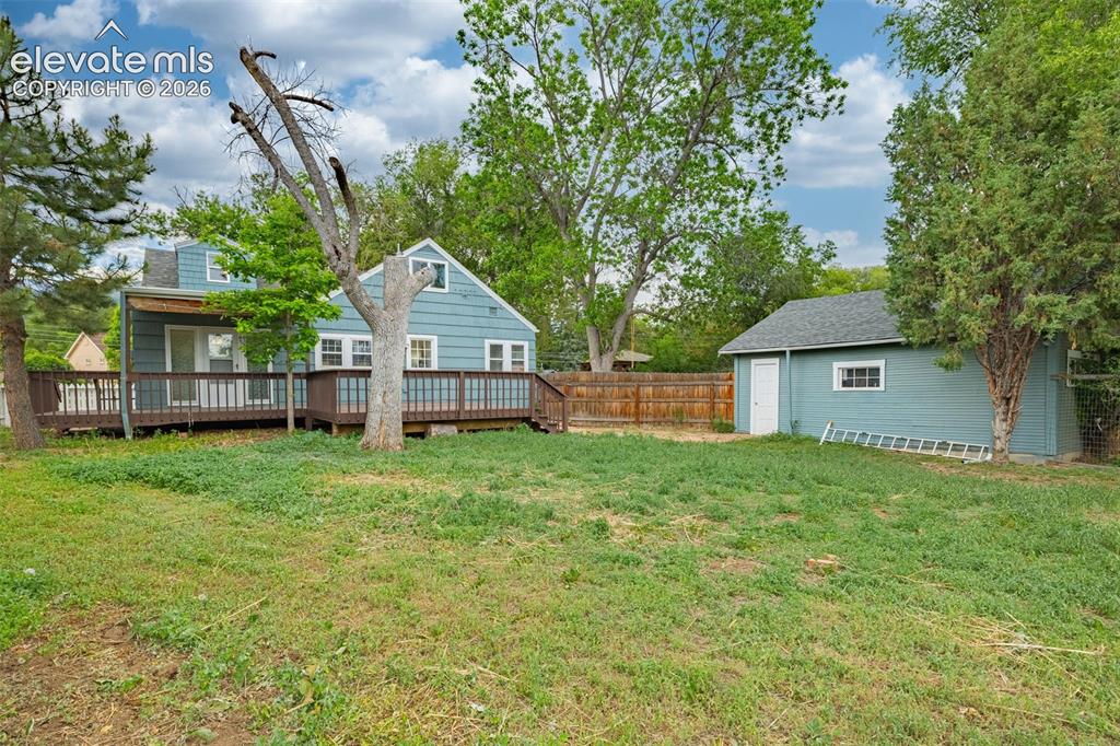 Image 45 of 50: Spacious backyard with a detached shed, a full-length wooden deck, and matu