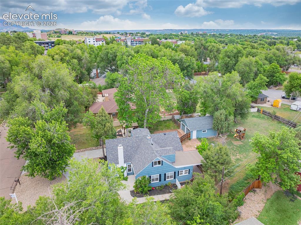 Image 47 of 50: Established residence featuring a blue exterior, white trim, a dark shingle