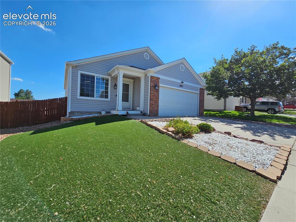 Caption: Single-story residence featuring light gray siding with brick accents and a two-car garage