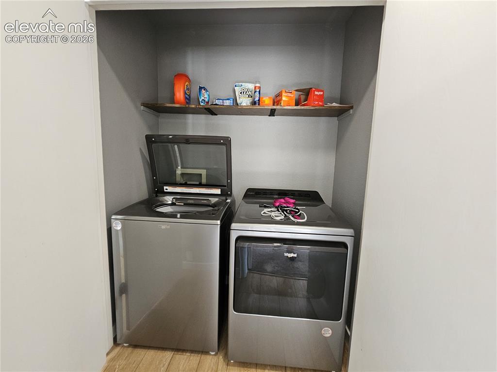 Image 13 of 26: Dedicated laundry alcove featuring a wood-finish shelf and wood-finish floo