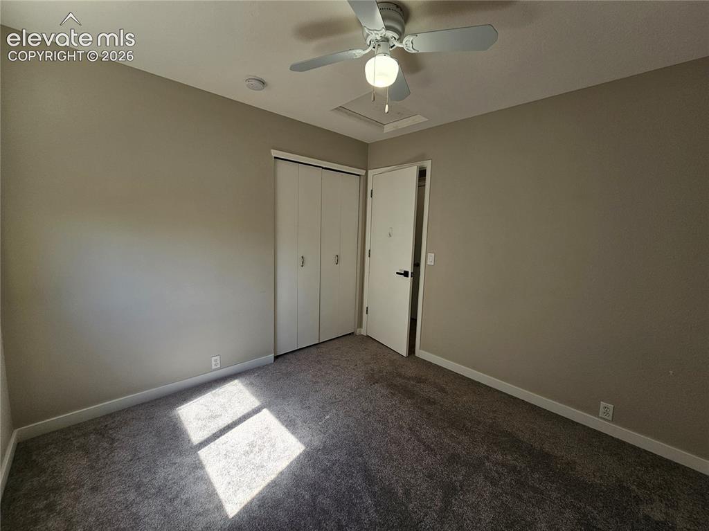 Image 15 of 26: Neutral-toned walls and grey carpeting complement a ceiling fan with integr