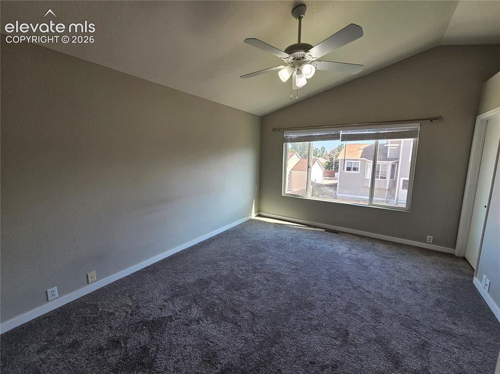 Image 18 of 26: Spacious room featuring vaulted ceilings, a large window, neutral wall tone