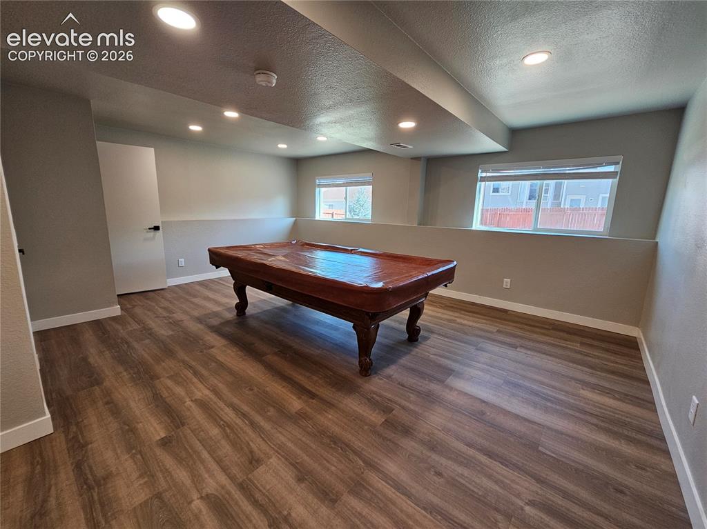 Image 20 of 26: Spacious recreation room featuring wood-finish flooring, recessed lighting,