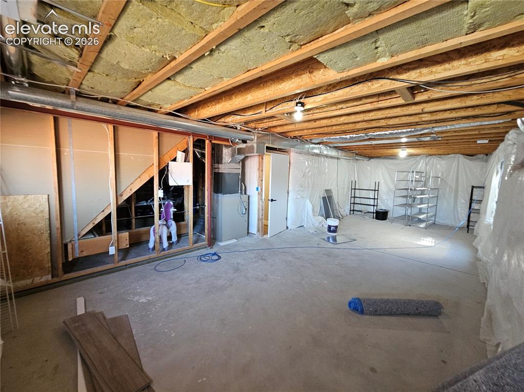 Image 22 of 26: Unfinished basement featuring exposed wood joists, ceiling insulation, and